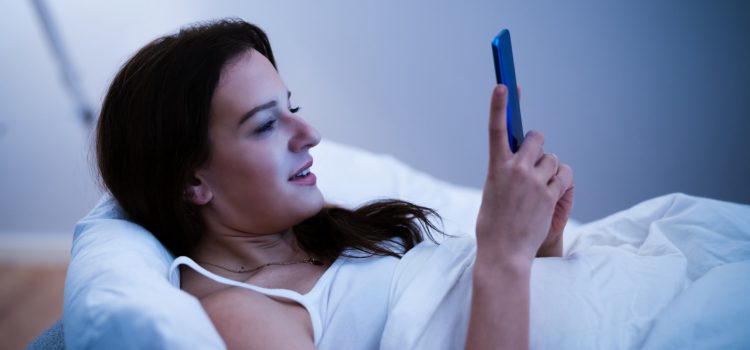 Kvinna använder mobilen i sängen